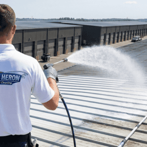 Blue Heron Cleaning technician performing a professional soft wash on a commercial metal roof in Conyers, Georgia.